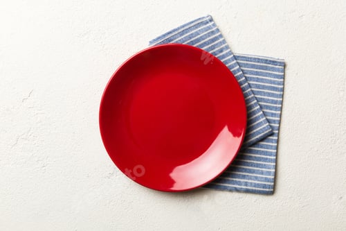 Preview: Top view on colored background empty round red plate on tablecloth for food. Empty dish on napkin