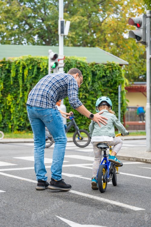 Preview: Happy family father teaches child daughter to ride public bike on traffic playground of Prague