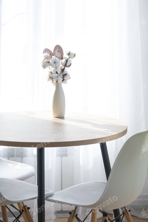 Preview: A bouquet of cotton twigs in a vase on a round table with an Easter decor of eggs and an Easter bunn
