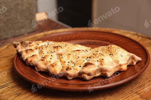 Preview: Plate with calzone on wooden table in restaurant. Fresh from oven