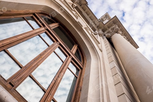 Preview: Large historic building with large columns, seen at a low angle, with a sky in the background