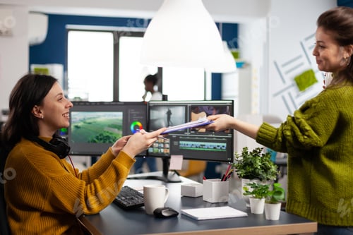 Preview: Creators drinking coffee and talking during office break sitting at desk in digital agency studio