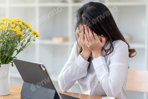 Preview: Image of a businesswoman holding a pen stressed frustrated bored with her hand off at their desk.