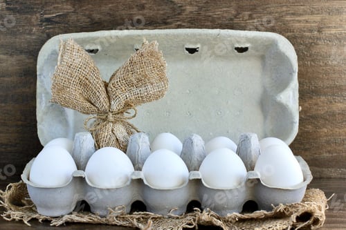 Preview: Chicken eggs, one decorated with burlap like a bunny rabbit in egg box. Concept of Easter and food.