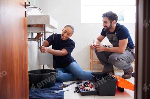 Preview: Male Plumber Teaching Female Apprentice To Fix Leaking Sink In Home Bathroom