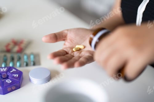 Preview: Sick illness woman hold two pill on hand pouring capsules from medication bottle take painkiller
