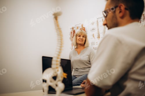 Preview: Medical assistant pointing at spine bones to explain diagnosis to senior woman for healthcare.