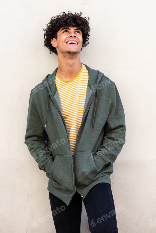 Preview: smiling young man standing by white wall and looking up