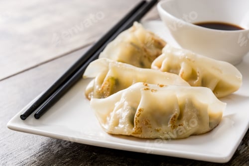 Preview: Delicious gyoza dumplings served on white plate with soy sauce and chopsticks
