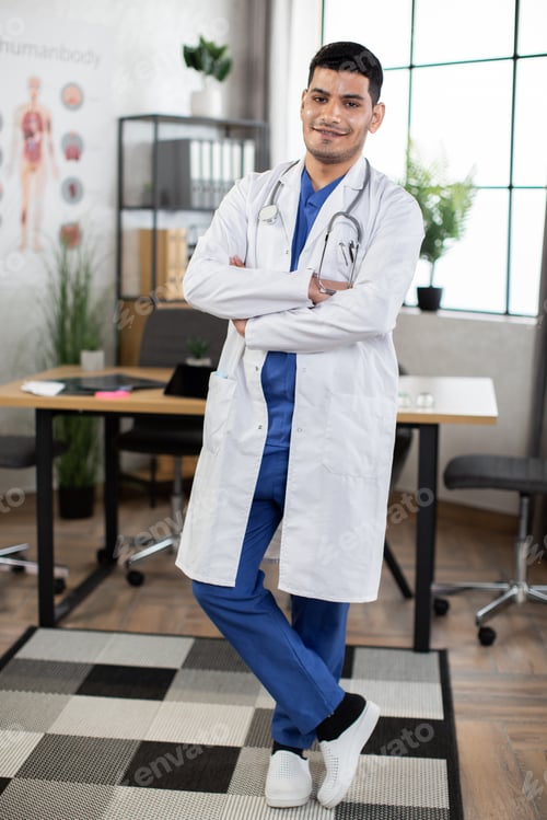Preview: Full length shot of male Malay healthcare practitioner, smiling indoors