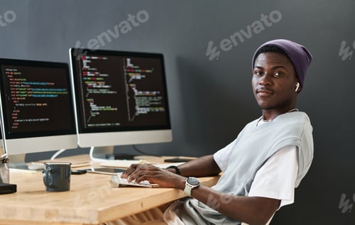 Preview: Young black man in casualwear keeping hands on computer keyboard