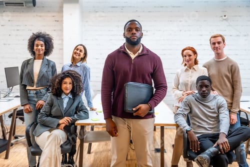 Preview: African man standing in a coworking surrounded by colleagues