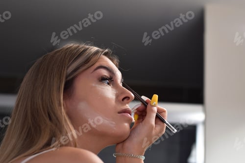 Preview: Young woman, teenage girl is applying make up in a bathroom, getting ready to go out