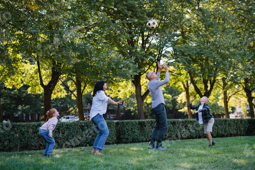 Preview: Happy little children with grandparents playing with football outdoors in park