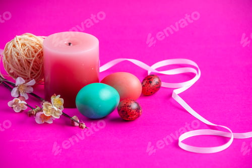 Preview: front view colored painted eggs with candle on pink background holiday spring concept novruz ethnic