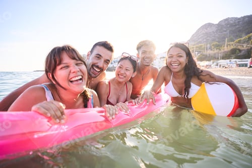 Preview: Group of diverse young gen z people in swimwear laughing looking at camera enjoying inside the sea