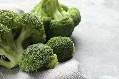 Preview: Fresh raw broccoli on gray textured table, closeup. Space for text