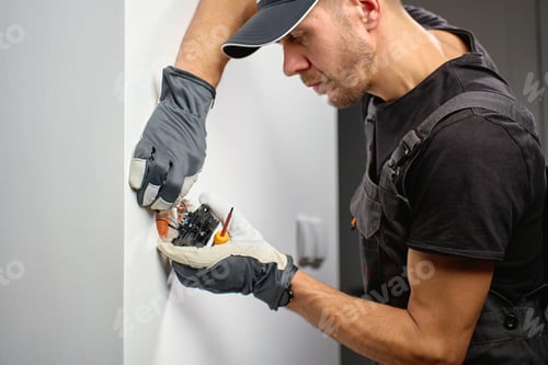 Preview: Electrician installing light switch in wall at home