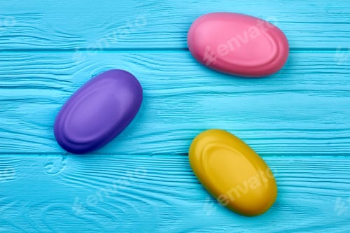 Preview: Three colored pieces of soap on blue wooden background.