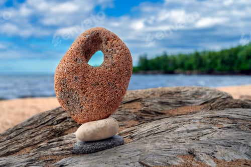 Preview: Rustic arrangement of balanced natural stones near a tranquil body of water