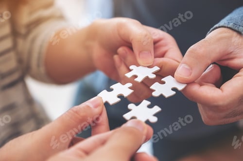 Preview: Closeup image of many people hands holding and putting a piece of white jigsaw puzzle together