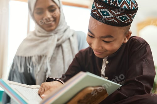 Preview: Shot of a young muslim mother and her son reading in the lounge at home