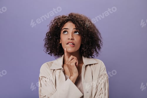 Preview: Black-haired girl in stylish jacket thoughtfully posing on purple background. Portrait of curly dar