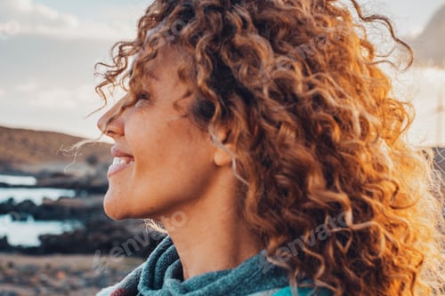 Preview: Woman outdoor smiling with long curly beautiful hair enjoying outdoor leisure activity alon