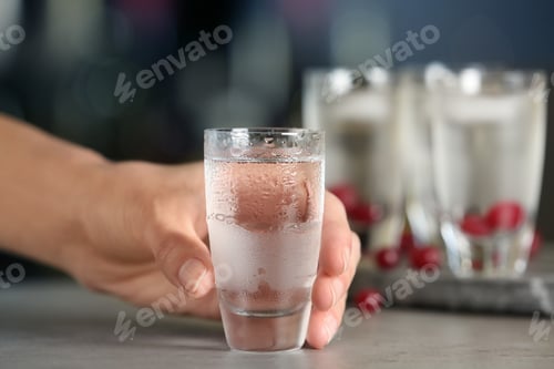 Preview: Woman with shot of vodka at table in bar, closeup