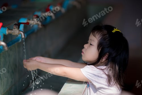 Preview: Asian girl wash her hands with tap at kindergarten school, after baby playing playground.