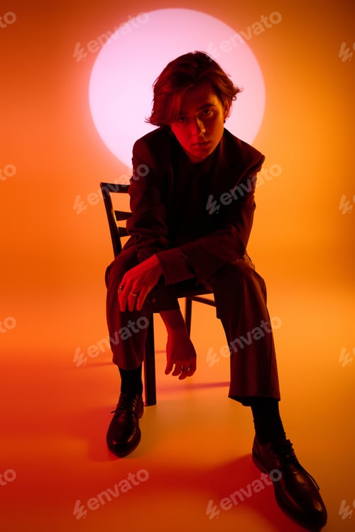 Preview: Stylish young man poses elegantly in front of a vibrant sun like backdrop