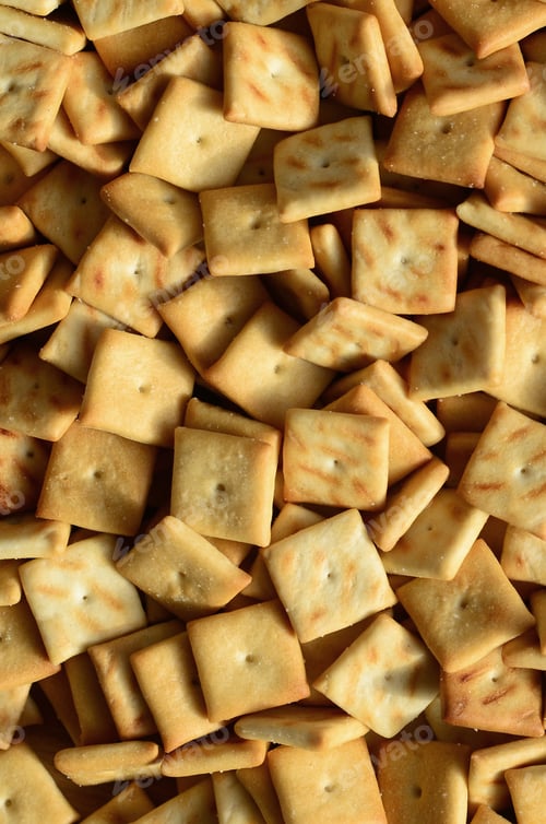Preview: A lot of small cookies are square shaped. A pattern of a yellow salt cracker. Background