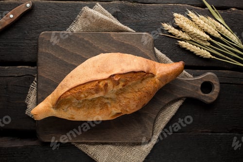 Preview: Fresh bread on a board with wheat on a wooden background