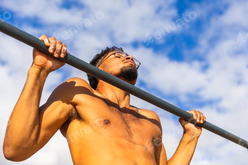 Preview: A man is doing pull-ups outdoors, fit person training