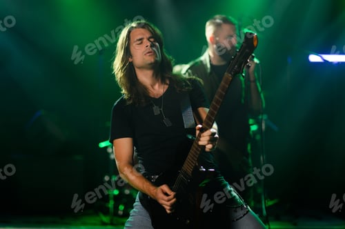 Preview: Guitarist performing live on stage with band in green lights