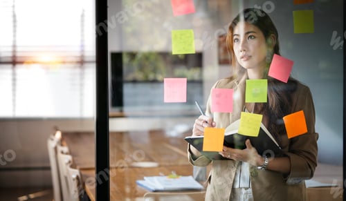 Preview: businesswoman using post it notes in glass wall to writing strategy business plan to success