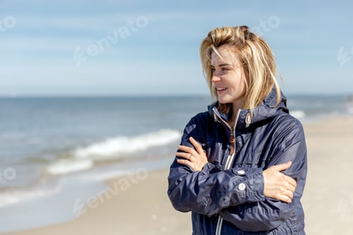 Preview: Young pretty woman at windy day walking on beach