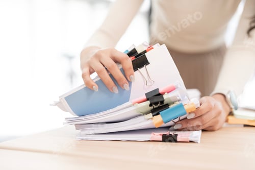 Preview: Businesswoman hands working in Stacks of paper files for searching and checking unfinished document