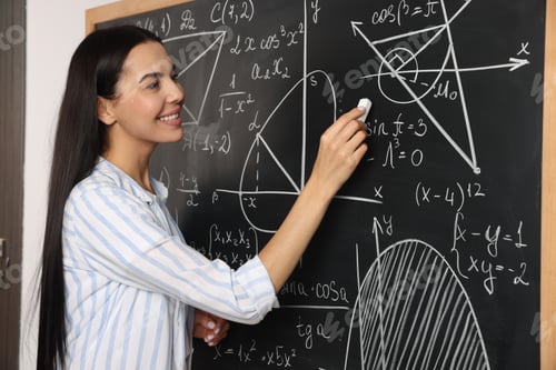Preview: Happy teacher explaining mathematics at chalkboard in classroom