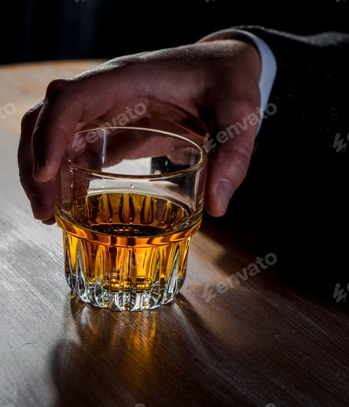 Preview: Man's hand holding a glass of whisky