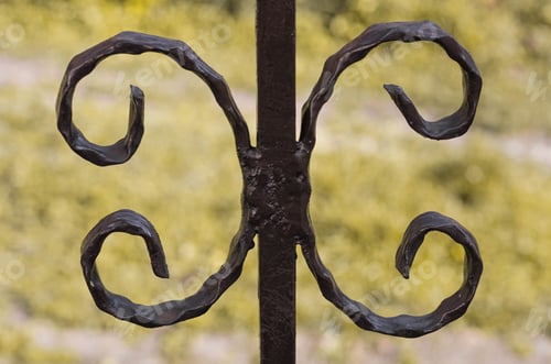 Preview: Intricate Dark Metalwork Against a Soft Yellow Background