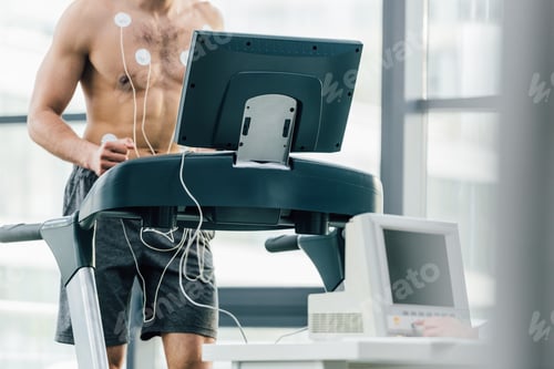 Preview: selective focus of sportsman with electrodes running on treadmill during endurance test in gym