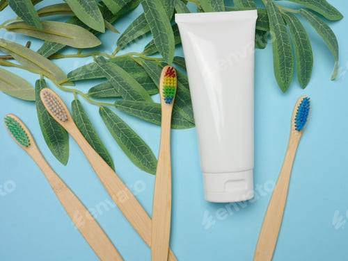 Preview: White plastic tube and bamboo toothbrush on blue background
