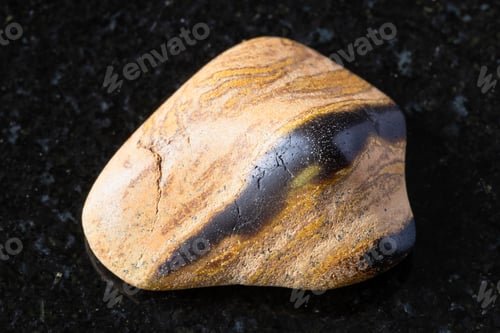 Preview: tumbled tuff sandstone mineral on on black granite