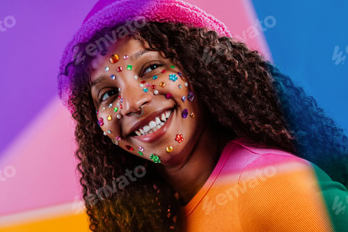 Preview: Young woman smiling with rhinestones on face and colorful background