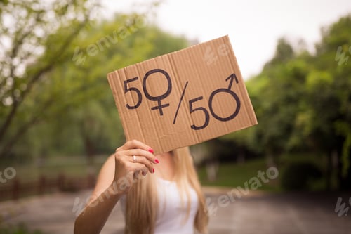 Preview: Gender equality concept as woman hands holding a paper sheet with male and female symbol over a