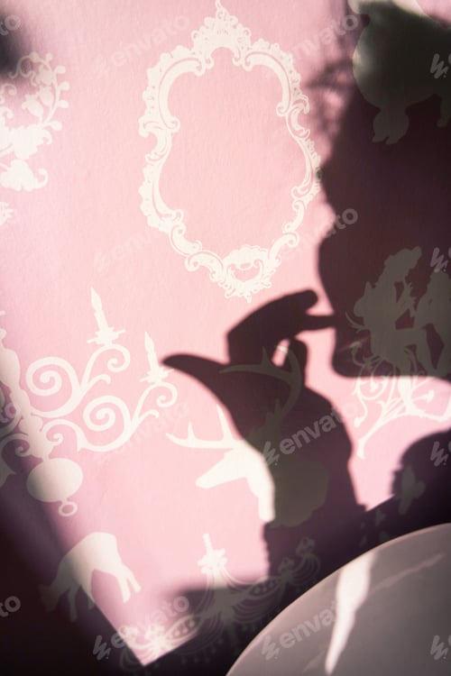 Preview: Girl looking at the mirror putting lipstick on en her lips, shadow silhouette on the pink wall .
