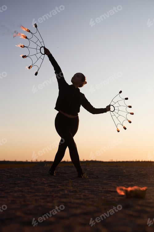 Preview: Female Artist Dancing with Fire Fans on Sunset Sky
