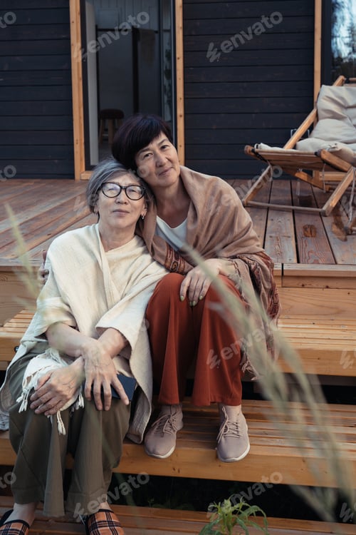 Preview: Two women sitting outdoors on suburb house terrace in cool summer day
