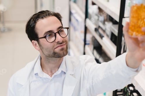 Preview: Druggist stretching to pills, vitamins, painkillers, medicines at pharmacy shelves in drugstore